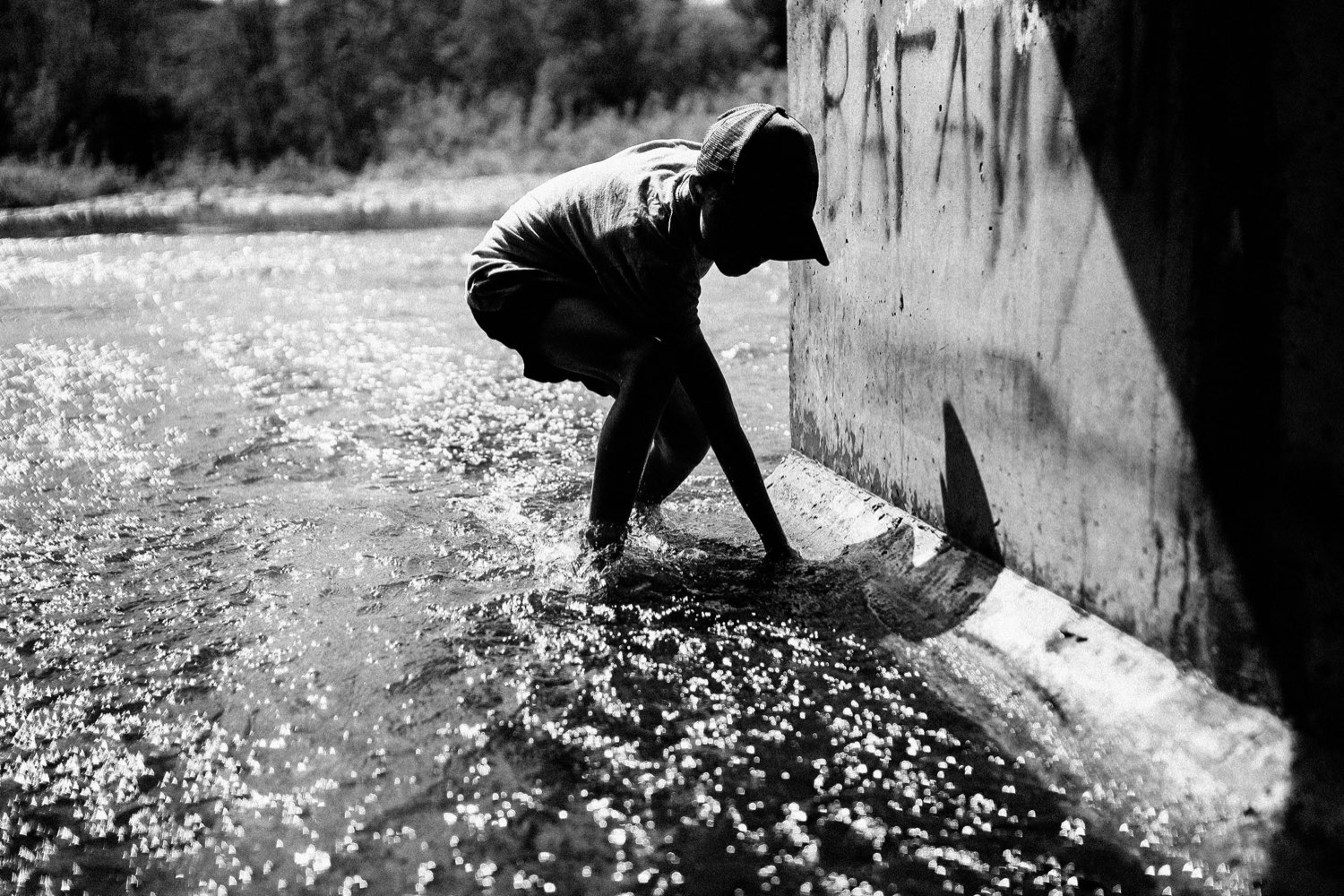 Чёрно-белый плёночный кадр: силуэт ребёнка у искрящейся воды